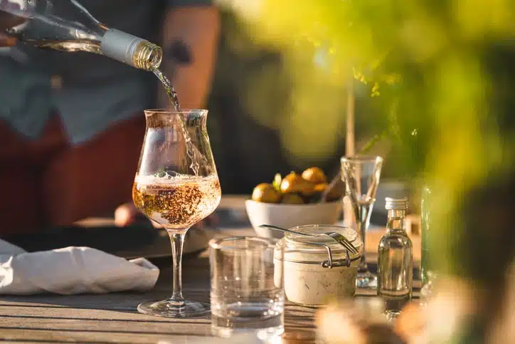 Man Pouring Up Rose Wine At Midsummer Dinner