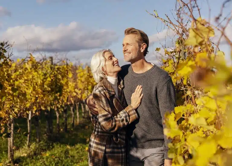 couple souriant au milieu des vignes d'automne