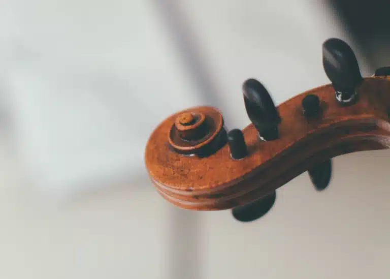 Close-up of a violin scroll in front of a blurred sheet of music